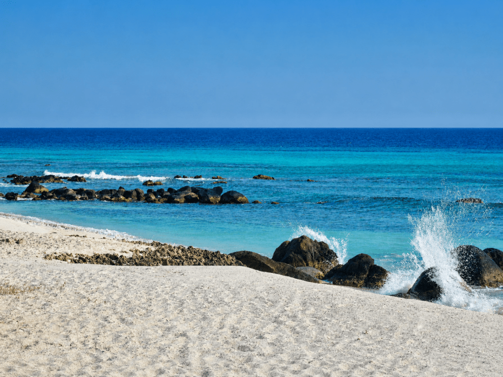 Arashi Beach Aruba met wit zand, rotsen en blauwe Caribische Zee