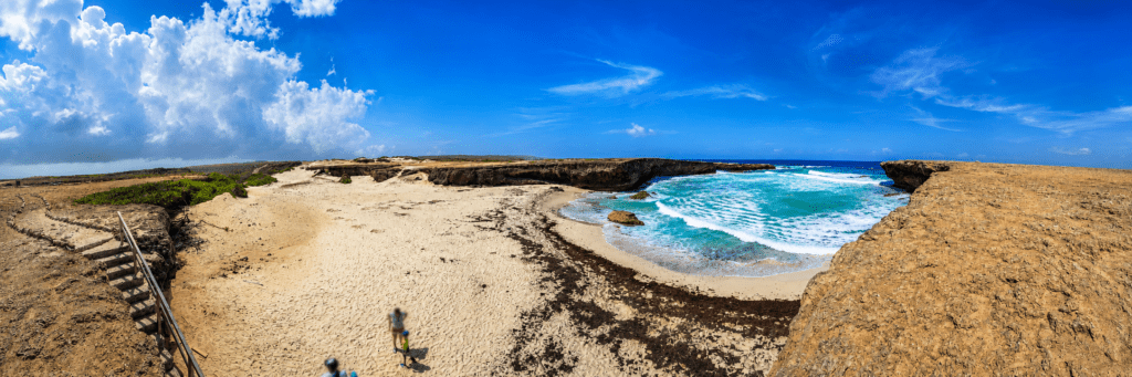 Turquoise baai tussen de ruige kliffen bij Boca Prins Aruba