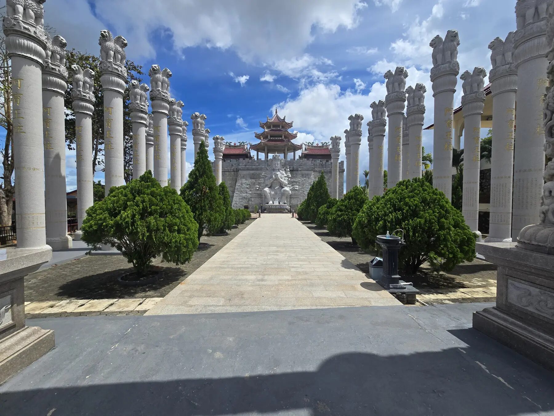 Pad tussen gebeeldhouwde stenen zuilen bij de 500 Lohan Temple op Bintan