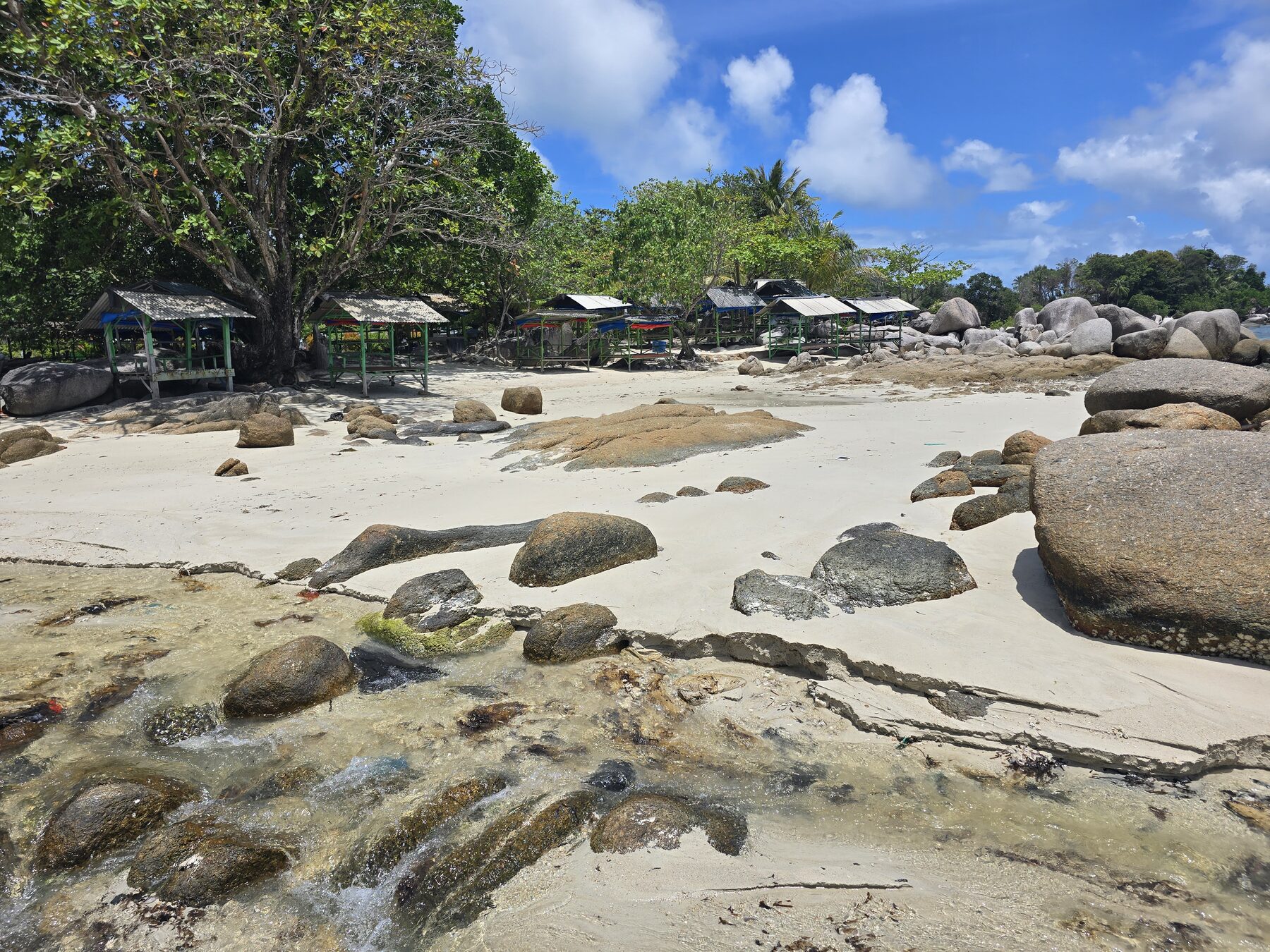 Zandstrand met grote rotsen en bomen op Bintan
