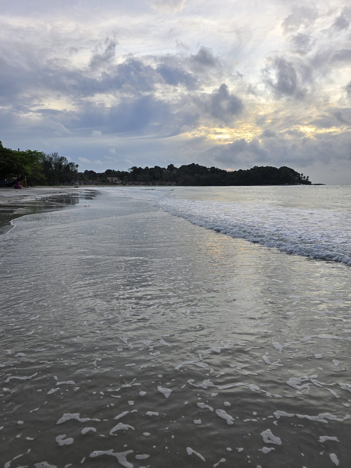 Rustige zee met avondlicht en een donkere kustlijn op Bintan