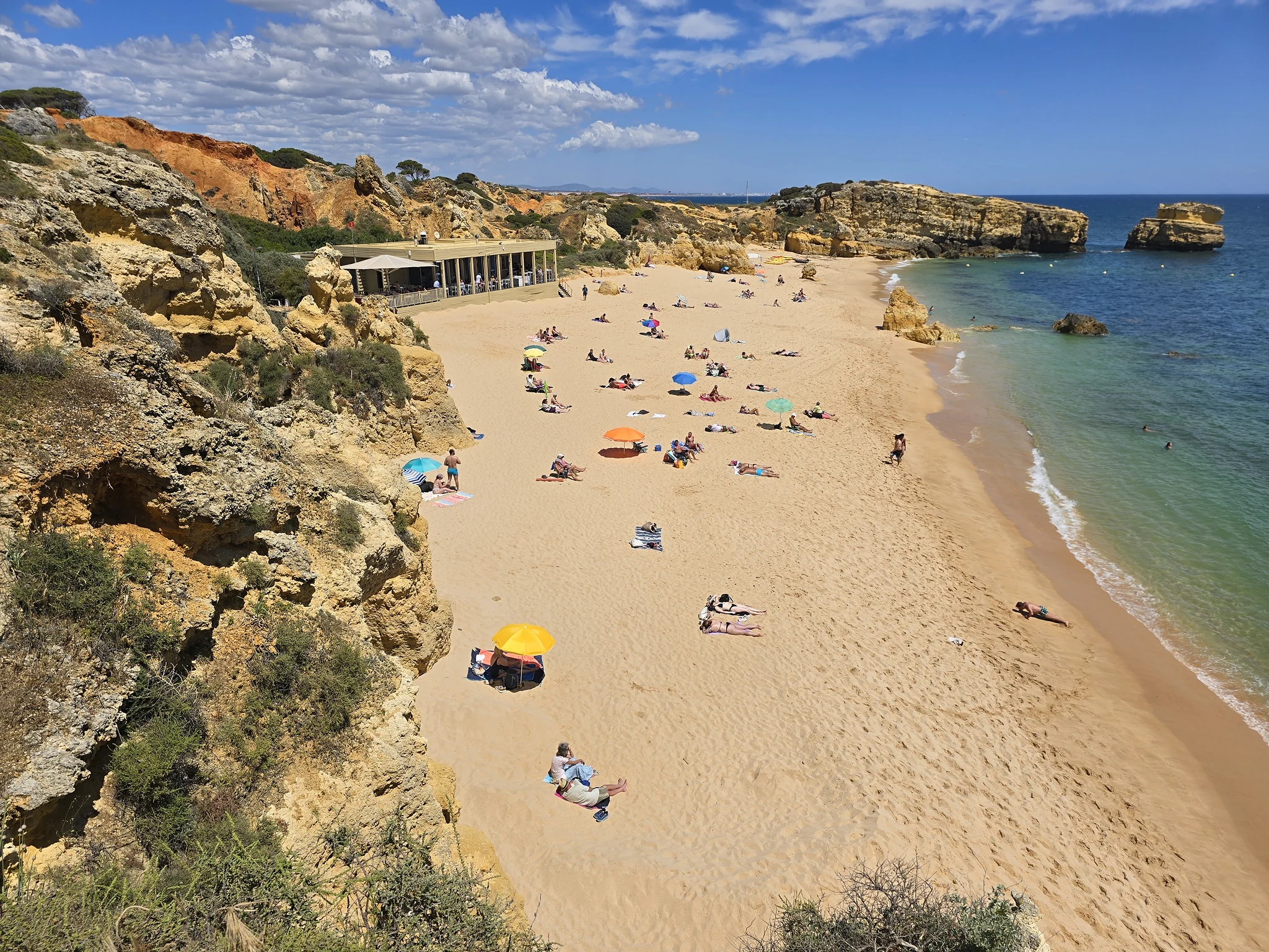 Praia de São Rafael met goudkleurige rotsen, zandstrand en zee.