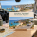 AI illustration with a postcard for Getting Around — Albufeira & Algarve, beside a window overlooking the Algarve.